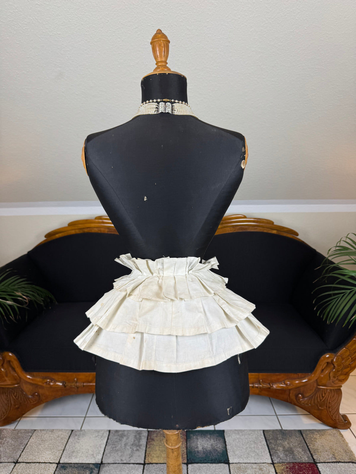 Victorian white linen four‑tier bustle pad c.1898 with pleated tiers and cotton waist tie.
