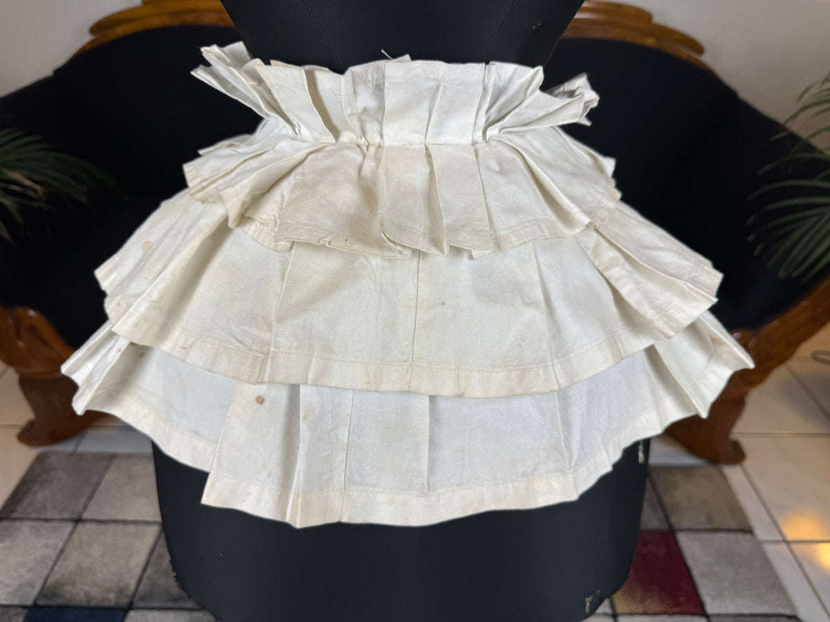 Victorian white linen four‑tier bustle pad c.1898 with pleated tiers and cotton waist tie.