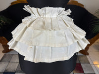 Victorian white linen four‑tier bustle pad c.1898 with pleated tiers and cotton waist tie.