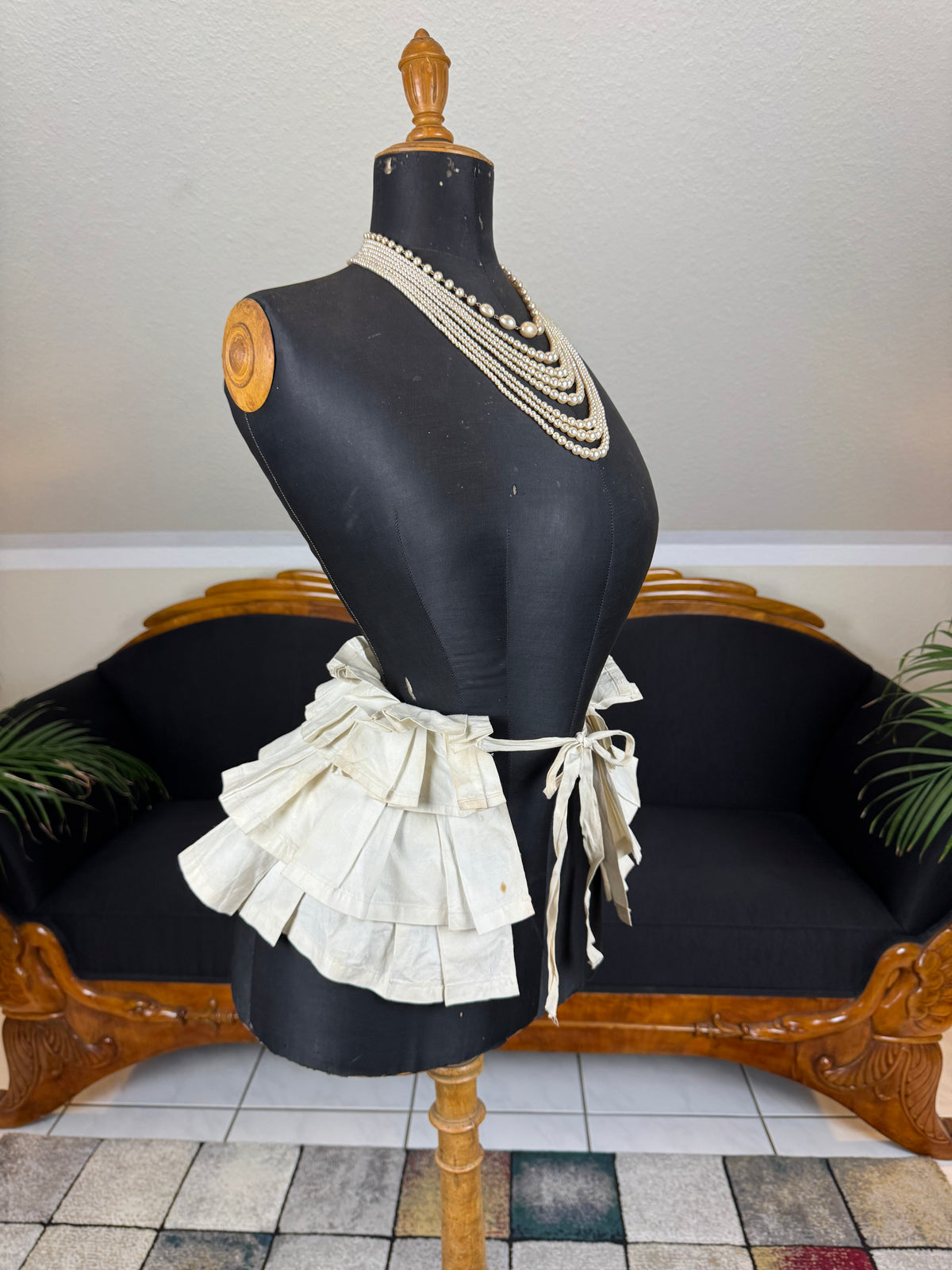 Victorian white linen four‑tier bustle pad c.1898 with pleated tiers and cotton waist tie.